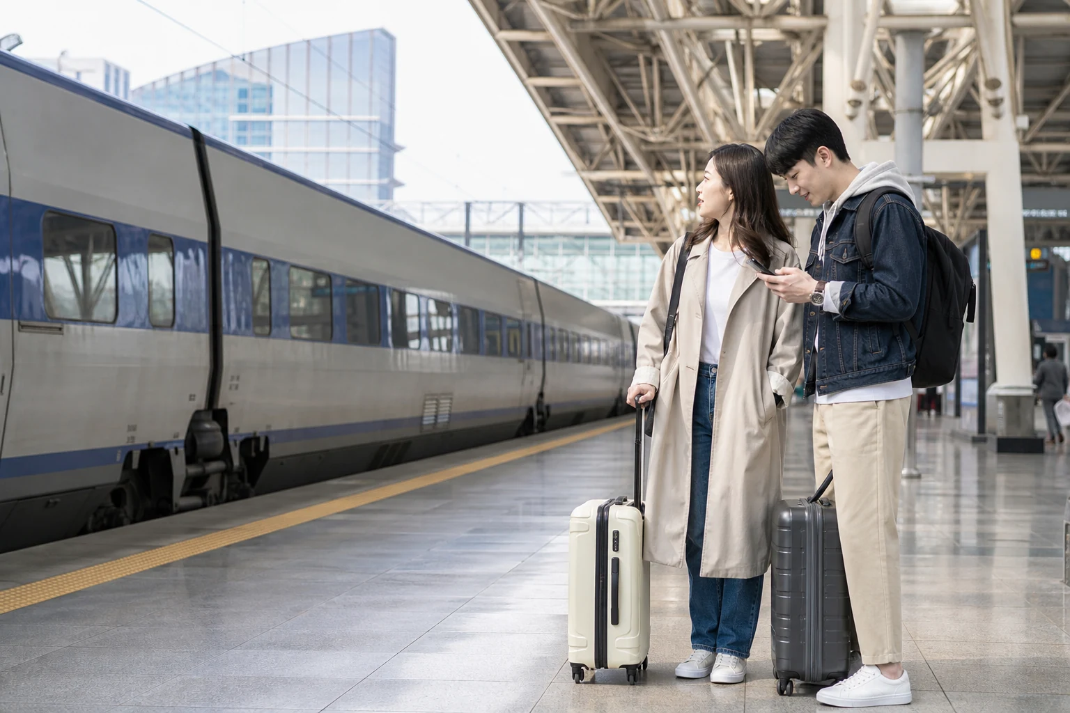 旅行者が荷物を持って韓国の都市間移動列車のホームでスマホを確認